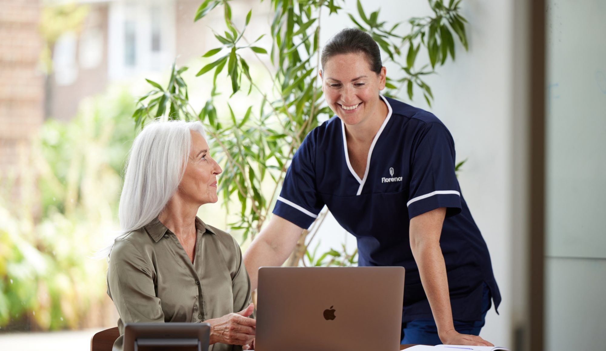 Two female healthcare professionals using a laptop to manage and fill rota gaps for contingent workforce management.